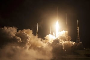 White rocket launching at night surrounded by clouds