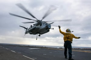 Military helicopter taking off from carrier in cloudy skies