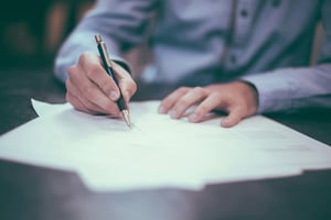 Businessman writing with pen on a cluster of papers