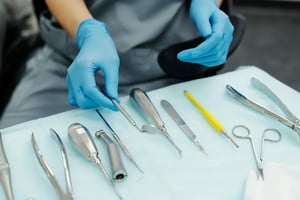 Medical tools on a table, doctor in blue gloves picking up a mirror