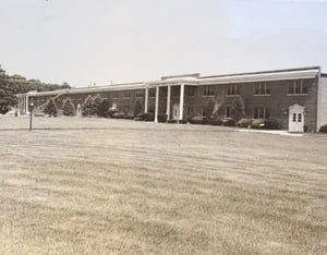 Photograph of a brick building with white trim and pillars in front