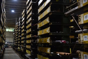 Yellow warehouse shelves holding steel bars and tubes